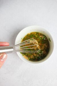 Whisking the olive oil and garlic mixture in a small bowl.