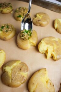 Pouring the olive oil mixture over the smashed potatoes.