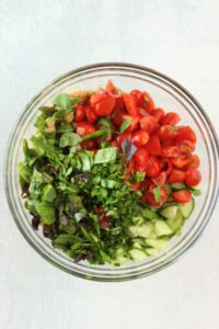 All of the salad ingredients are in a glass bowl and are ready to be tossed.
