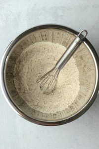 The protein powder and oat flour have been mixed together in a stainless steel bowl.
