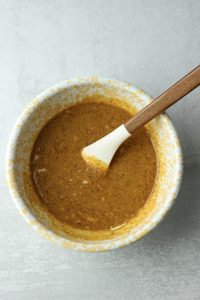 All of the wet ingredients have been mixed in a small yellow bowl. 