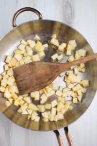 Cooking the apple chunks in water in a pan on the stove.