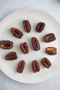 The dates are cut open and laid out on a plate. They are ready to be stuffed.