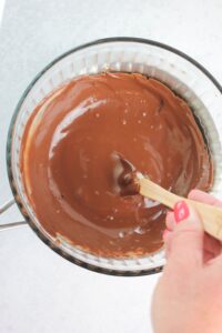 Melting and stirring the chocolate in a glass bowl.