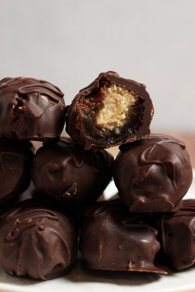 The coconut stuffed dates are stacked on a plate.