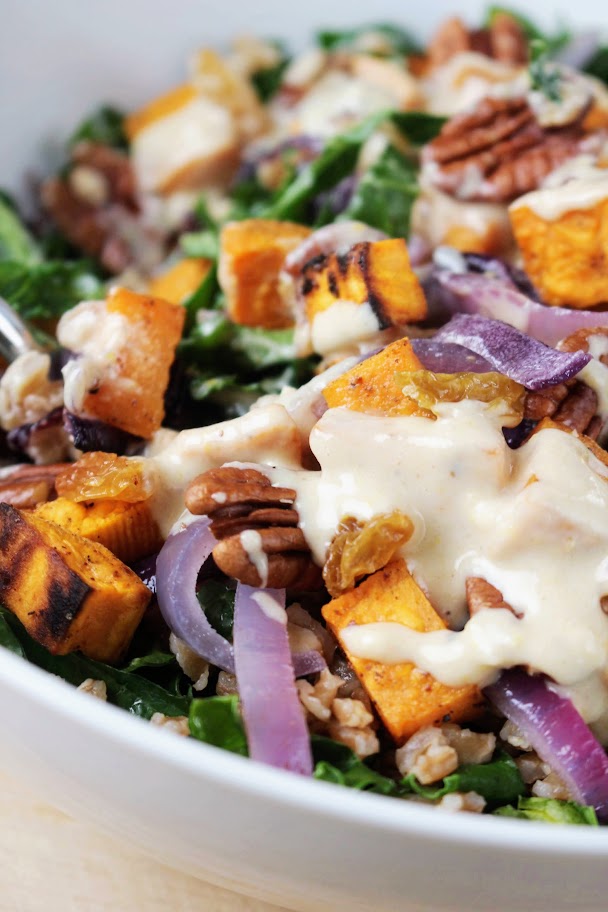 An up close picture of kale and sweet potato salad with orange tahini dressing.