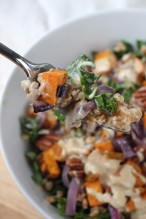 A forkful of kale and sweet potato salad with orange tahini dressing.