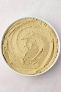 The bean dip has been spread into a shallow white bowl.