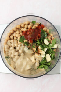 All of the ingredients have been added to the bowl of a food processor.