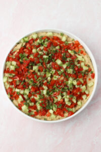 The vegetables and mint have been sprinkled over the top of the bean dip.