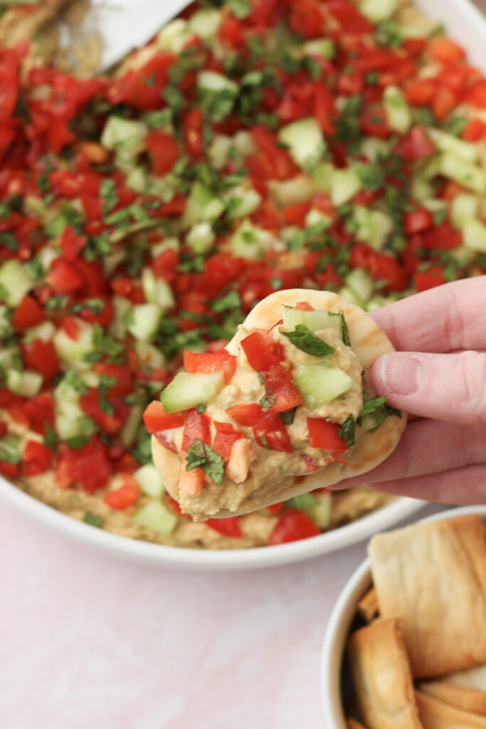 Holding one pita bread with bean dip.