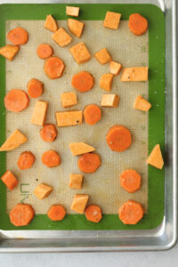 The carrot and sweet potato chunks are on a tray, ready to be roasted.