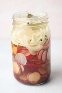 The pickled radish ingredients have been layered into a large mason jar.