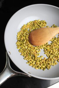Toasting pumpkin seeds in a pan.