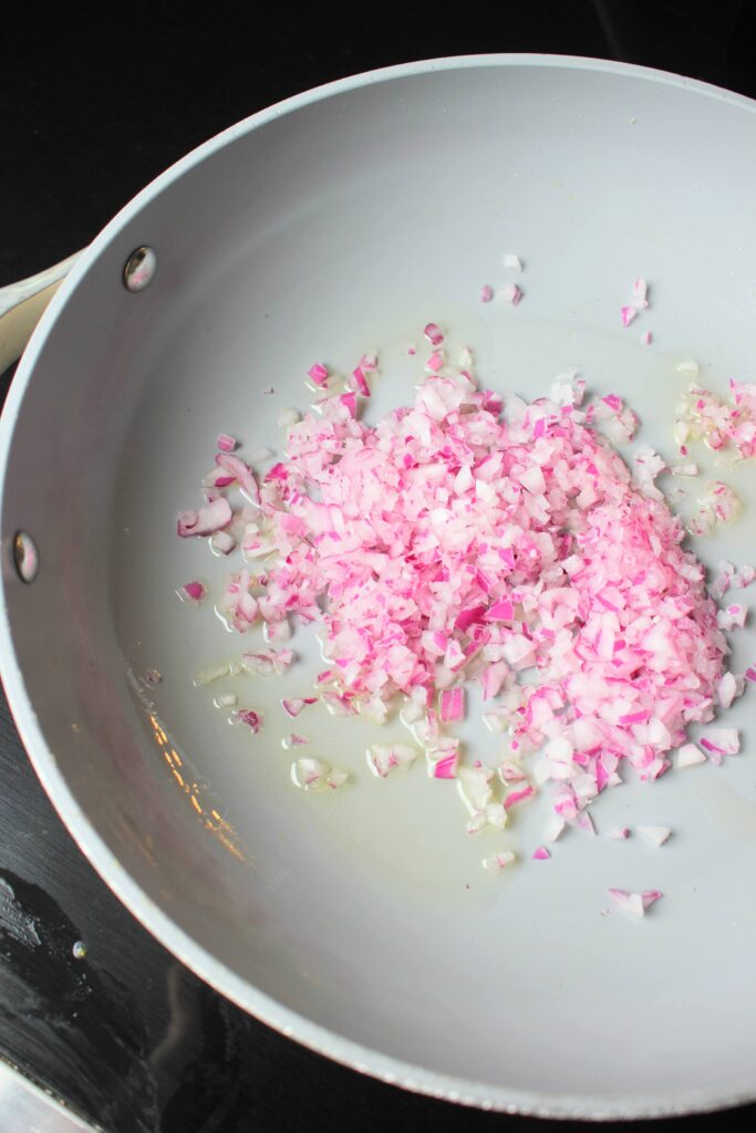 Sautéing red onion in a hot pan.