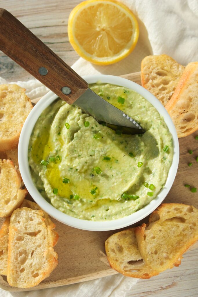 The bean dip is in a bowl with bread and is ready to serve.