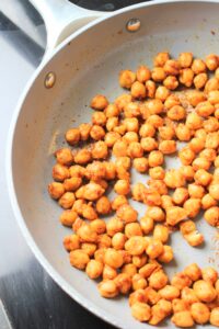 The chickpeas are sauteing in a pan.