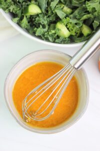 Whisking the dressing in a small bowl.