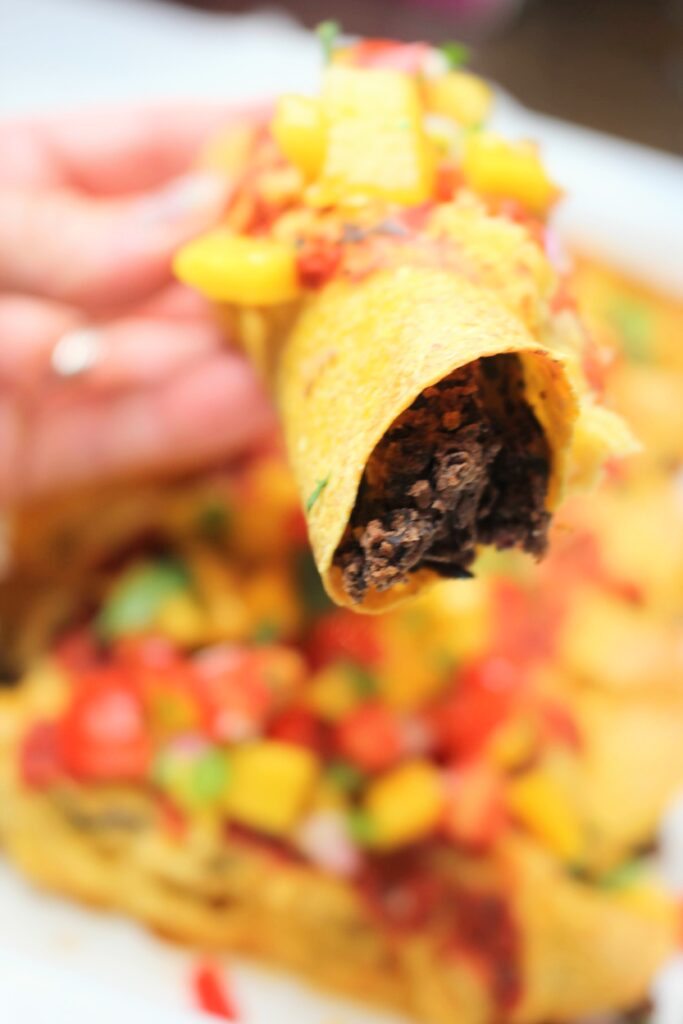 Holding up one taquito up close.