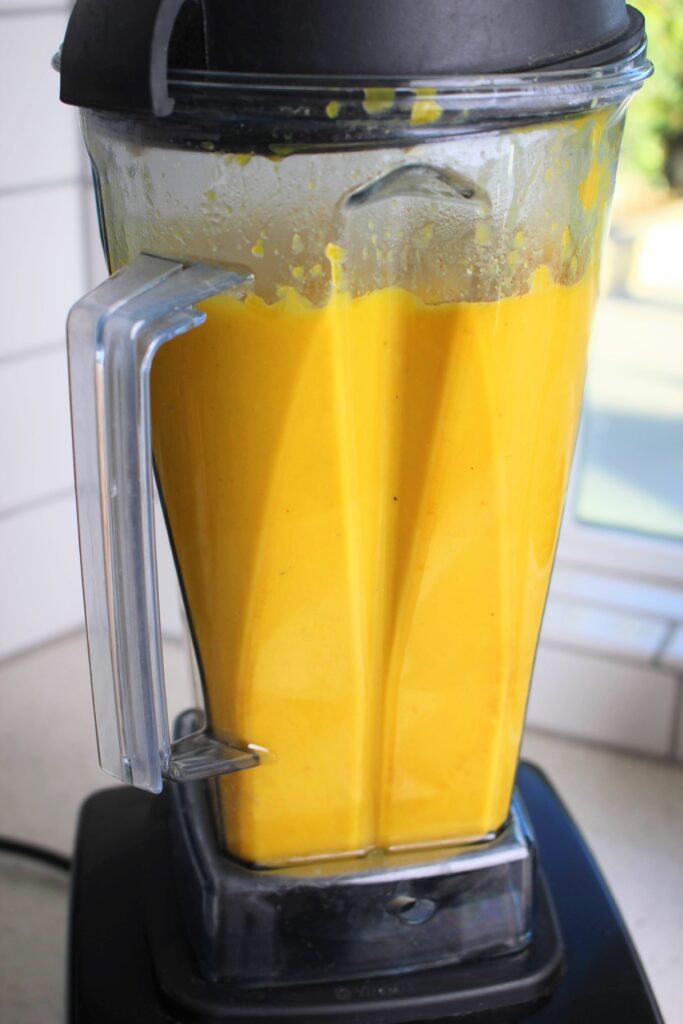 The pumpkin soup is all blended up in a blender.