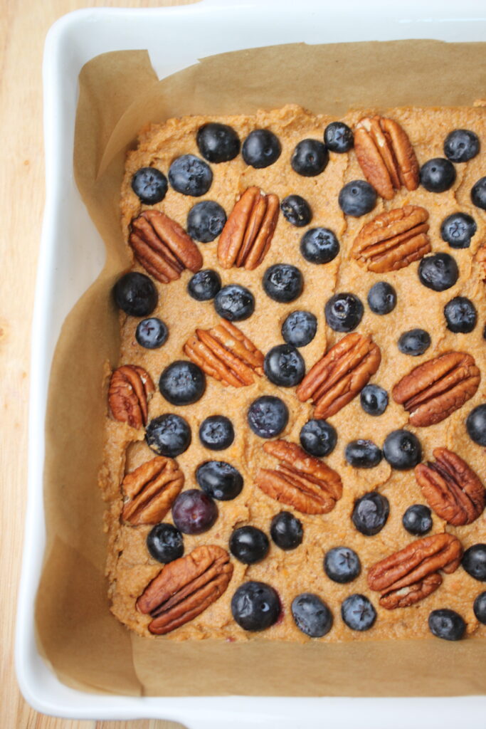 The breakfast bars are topped with pecans and blueberries and ready to go into the oven.