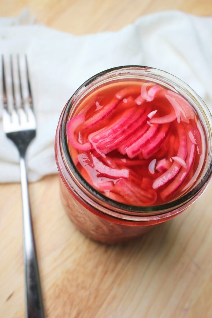 The pickled red onions are ready to eat in a mason jar.