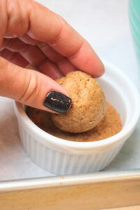Dipping a ball of dough into coconut sugar.