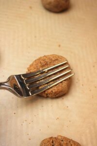 Pressing the fork into the top of the ball of dough to make a criss-cross design on top.