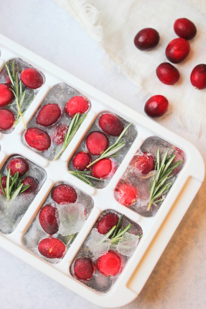 An ice cube tray of cranberry and rosemary ice cubes.