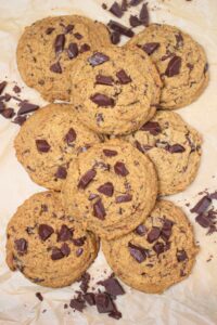 Finished vegan chocolate chip cookies on parchment paper.