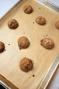 The baked cookies are on a cookie tray ready for the peanut butter cup to be pressed in.