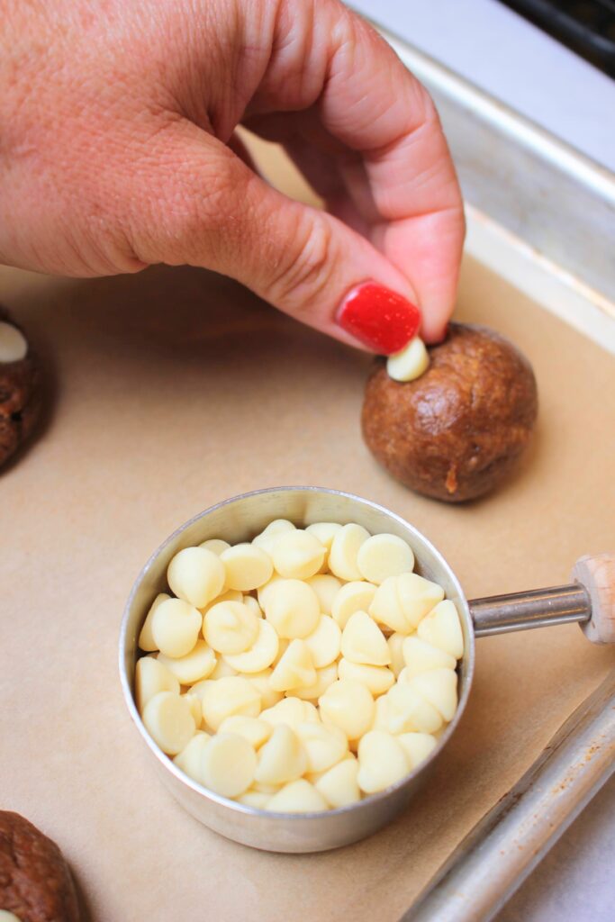 Pressing the white chocolate chips into the cookie dough balls.