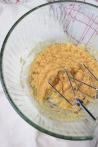 Using an electric mixer to beat the wet ingredients in a glass bowl.