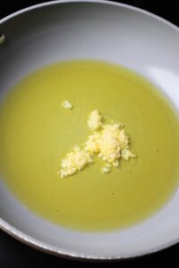 Olive oil and minced garlic heating up in a pan.