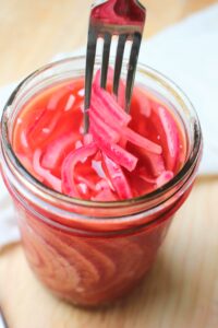 A mason jar of pickled red onion.