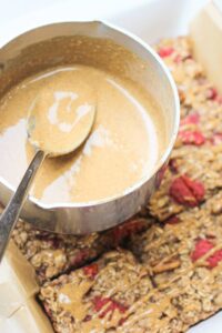 Warm almond butter drizzle in a sauce pan ready to put over the top of the bars.