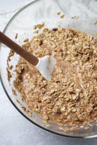 Stirring the dry and wet ingredients together in a glass bowl with a spatula.