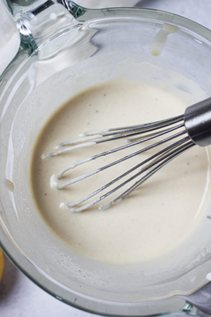 A whisk in a bowl of dressing and is ready to go.