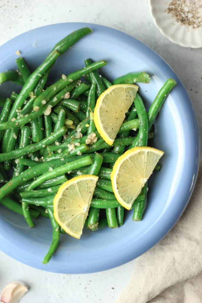 An up close picture of these green beans with fresh garlic on top.