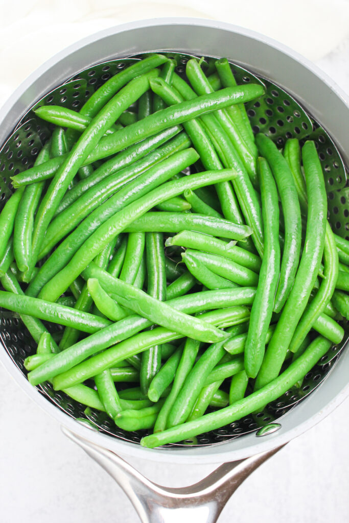 The green beans in a steamer basket and ready to start cooking.