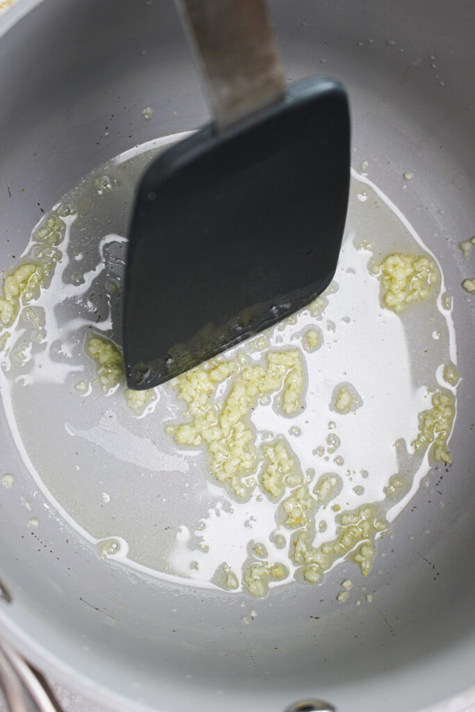 Cooking minced garlic in a saucepan with avocado oil.
