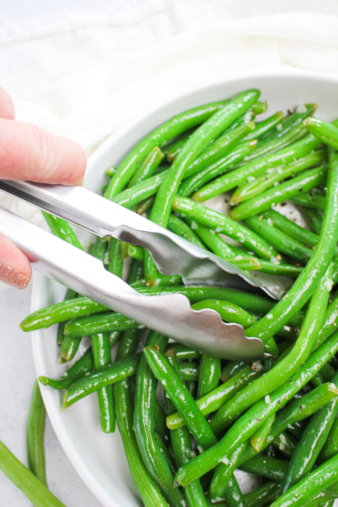 Serving the lemon garlic green beans with tongs.