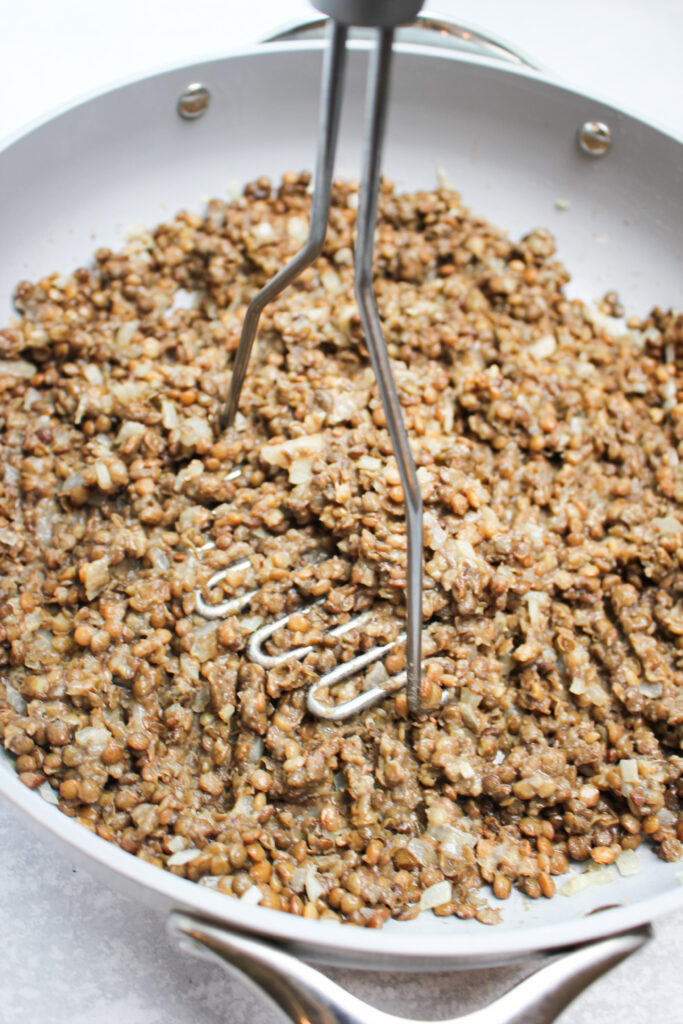 Mashing the lentils with a potato masher.