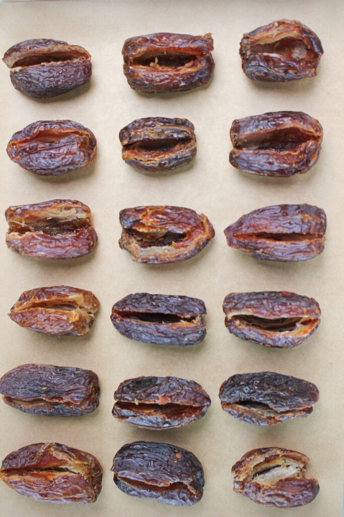 The dates are pitted and sliced on a tray and ready to be stuffed.