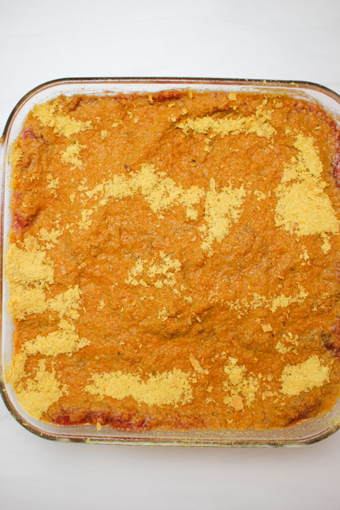 The casserole is topped with nutritional yeast and is ready to bake in the oven.