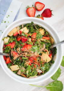 The dressing has been tossed into a strawberry and kale salad.