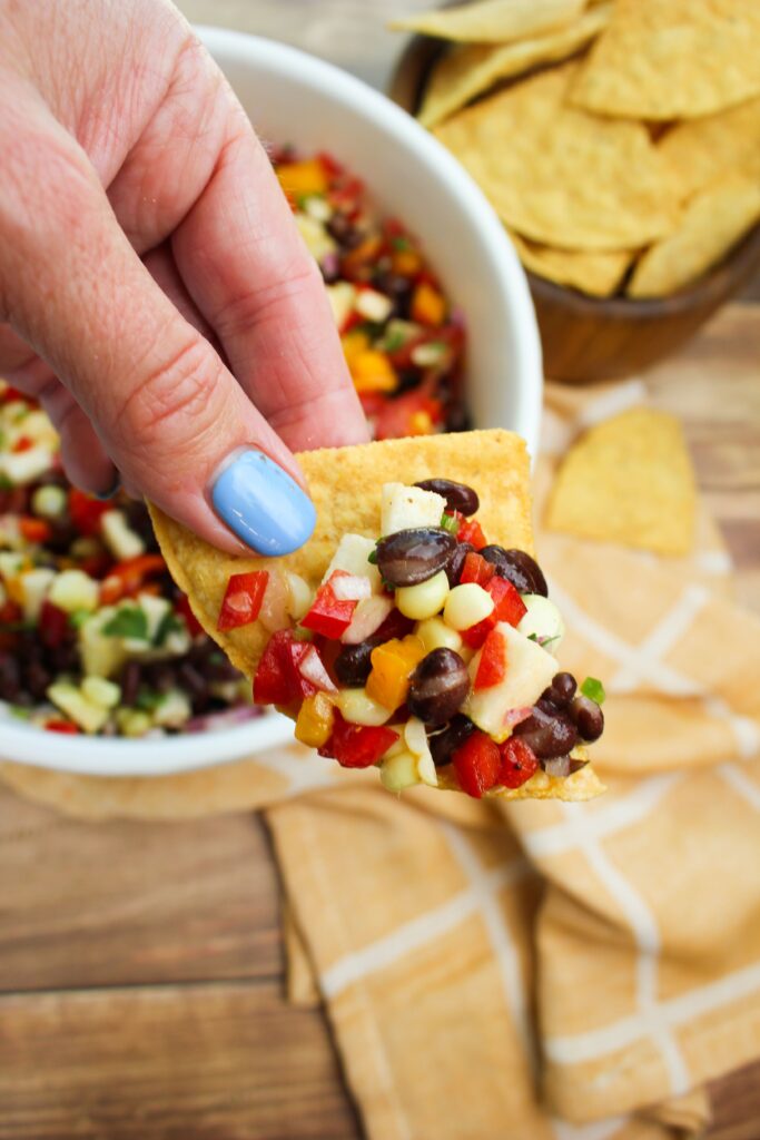 Holding a chip dipped into this black bean salsa.