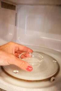 Removing the melted coconut oil from the microwave. 