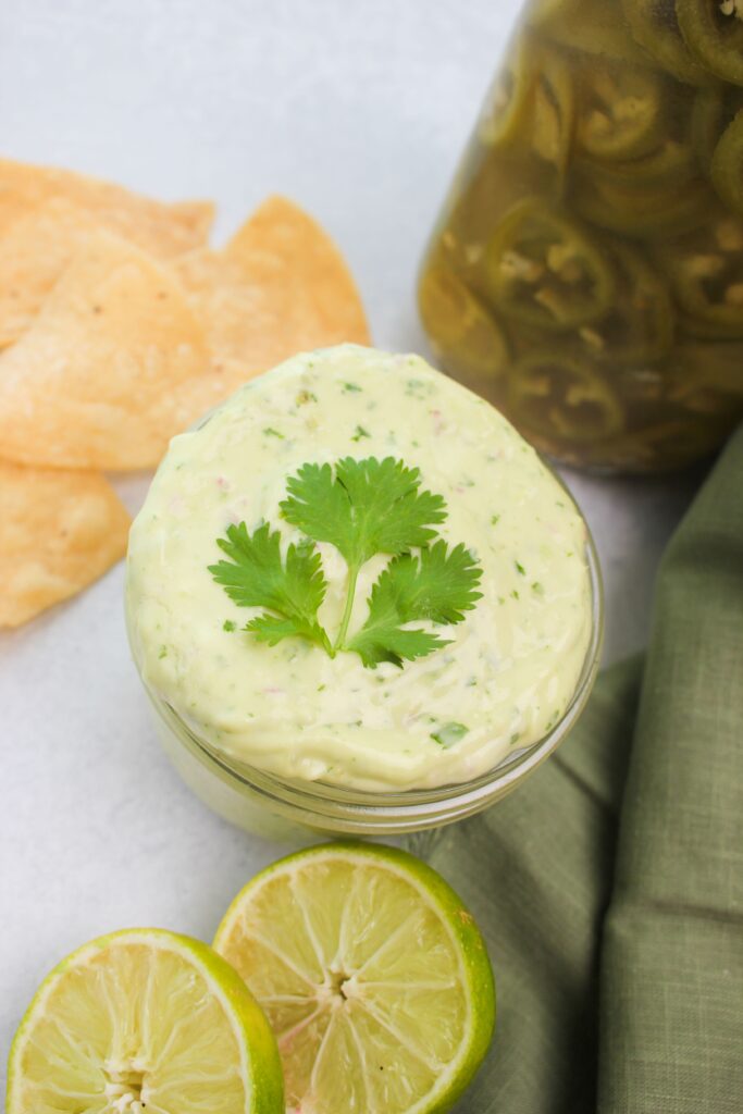 The dip is in a small glass bowl with tortilla chips and is ready to eat. 