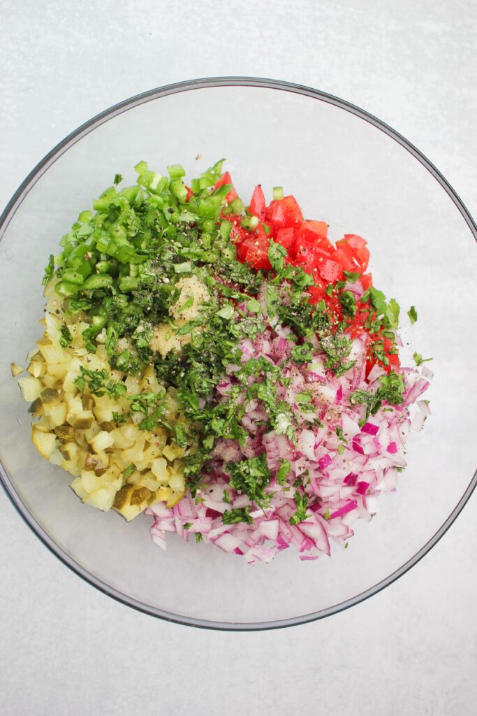 All of the ingredients in a large clear bowl and ready to get tossed.